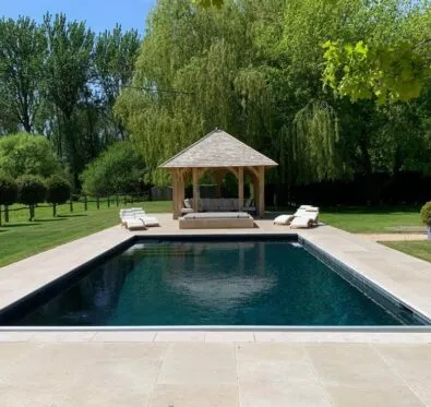 Poolcraft Ltd - An outside inground pool with a sandstone tile surround and a lounge area with a pergola